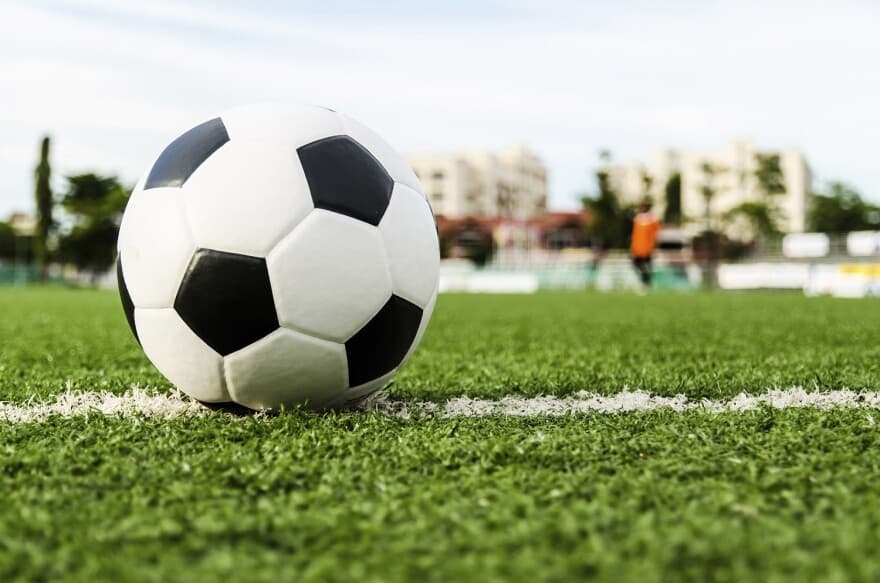 A football resting on the grass pitch line