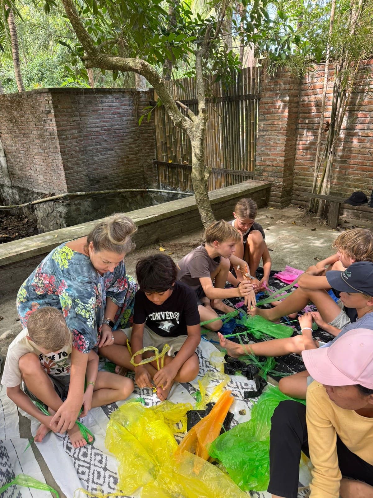 Students working together on a recycled plastic craft activity in the school garden