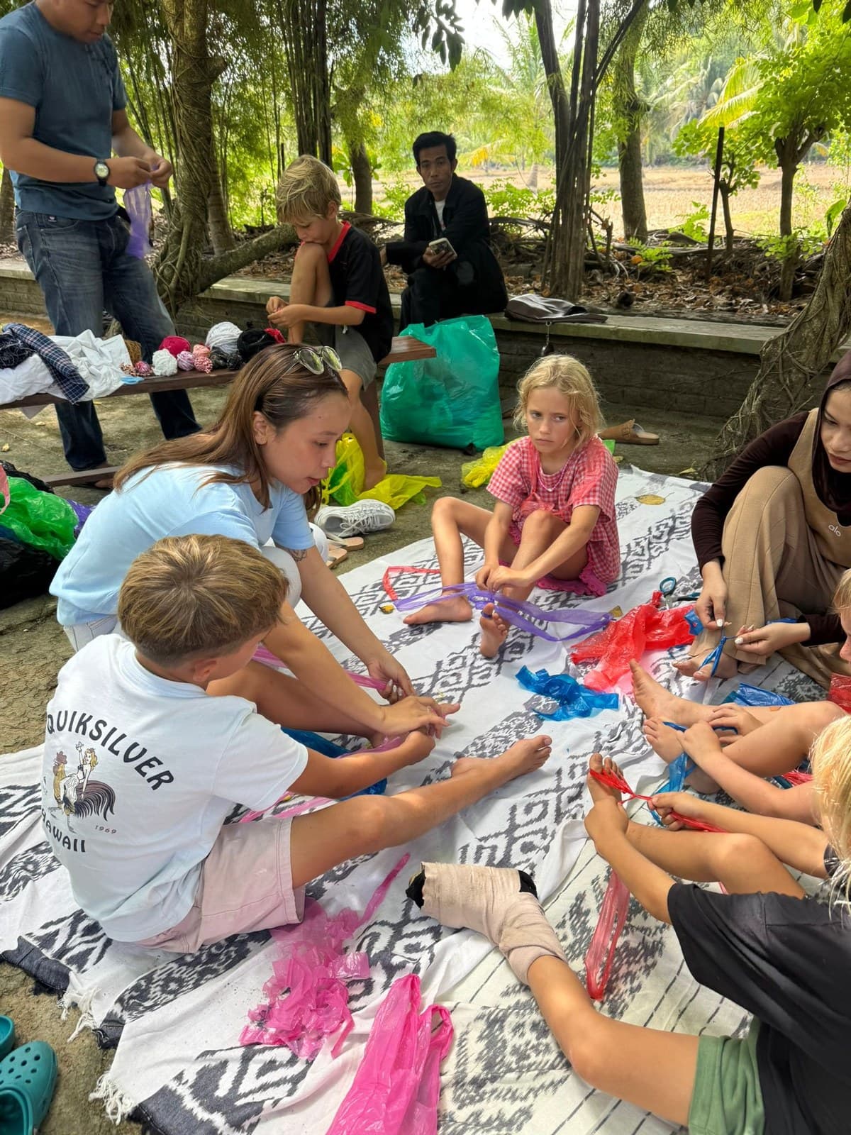 Students and staff weaving colourful recycled materials together during a craft session