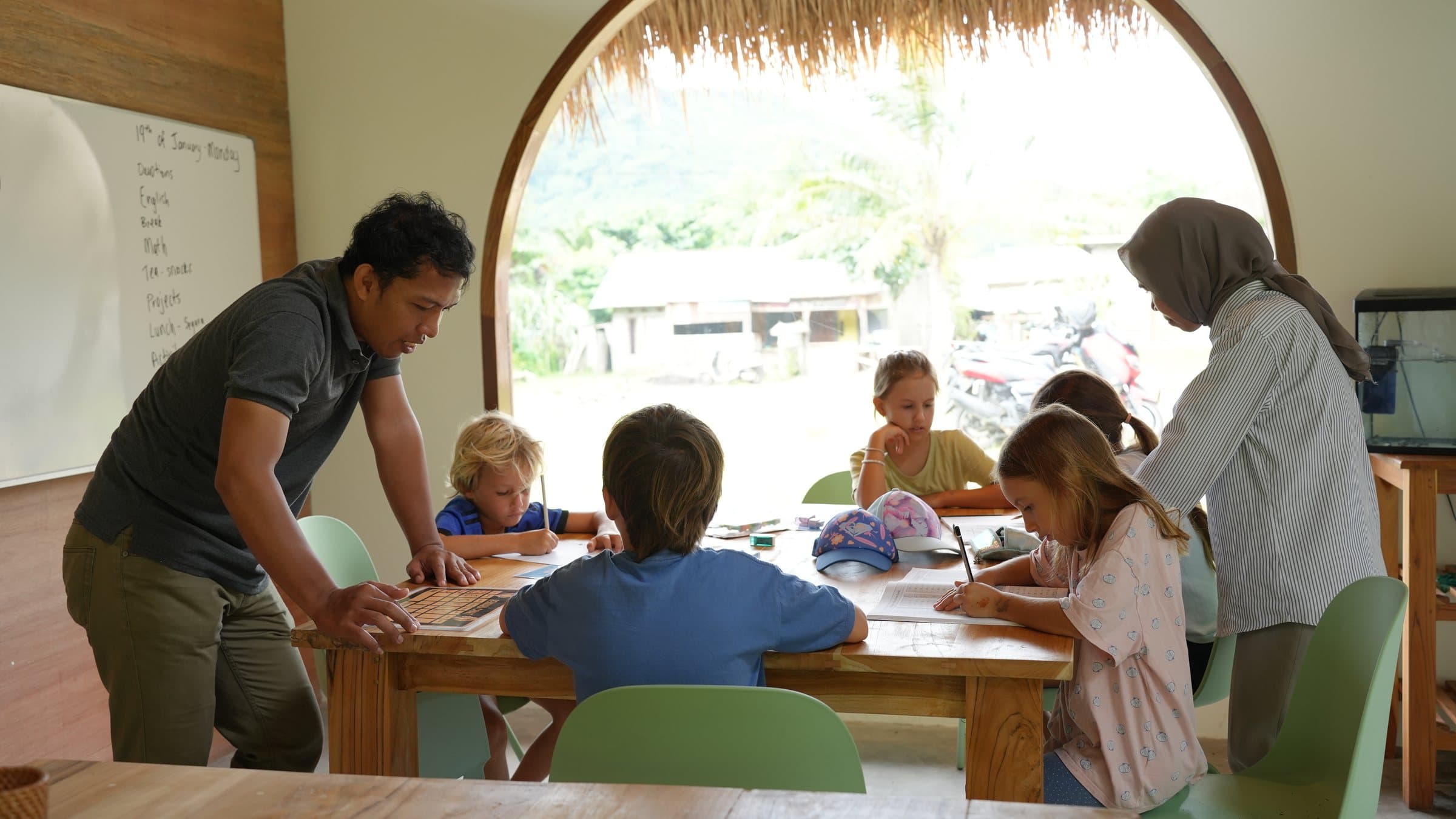 A teacher and teaching assistant helping students at Selong Bay School
