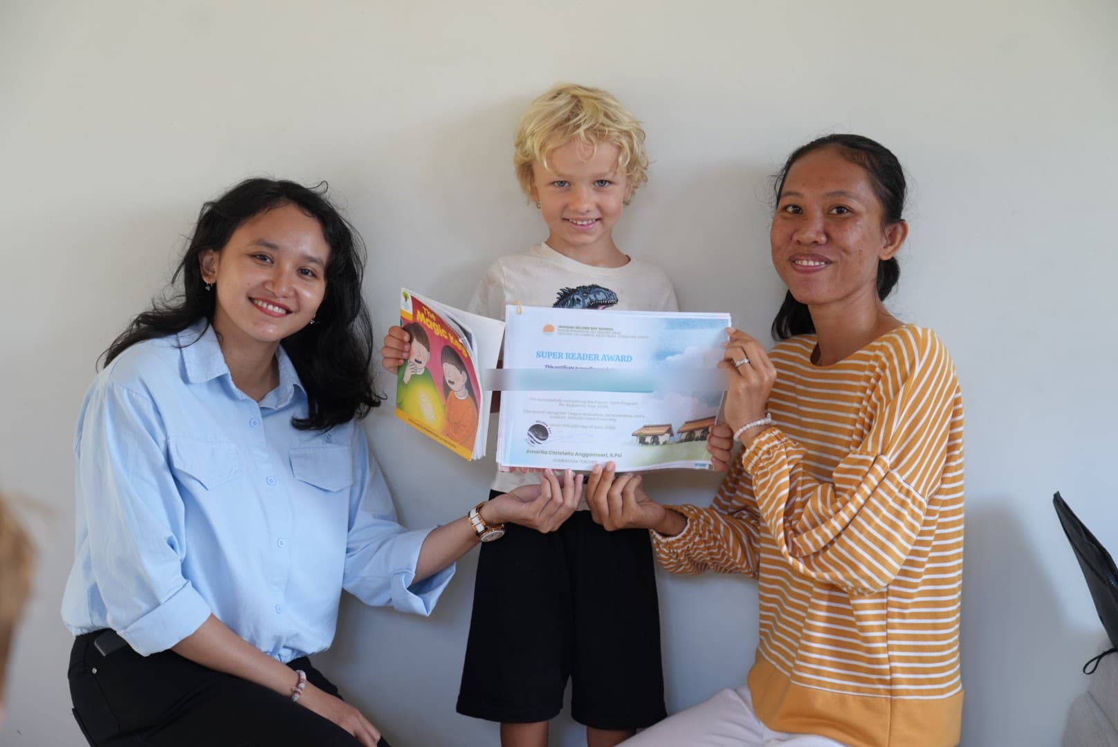 Ms Ella and a Selong Bay staff member celebrating a student's Super Reader Award certificate