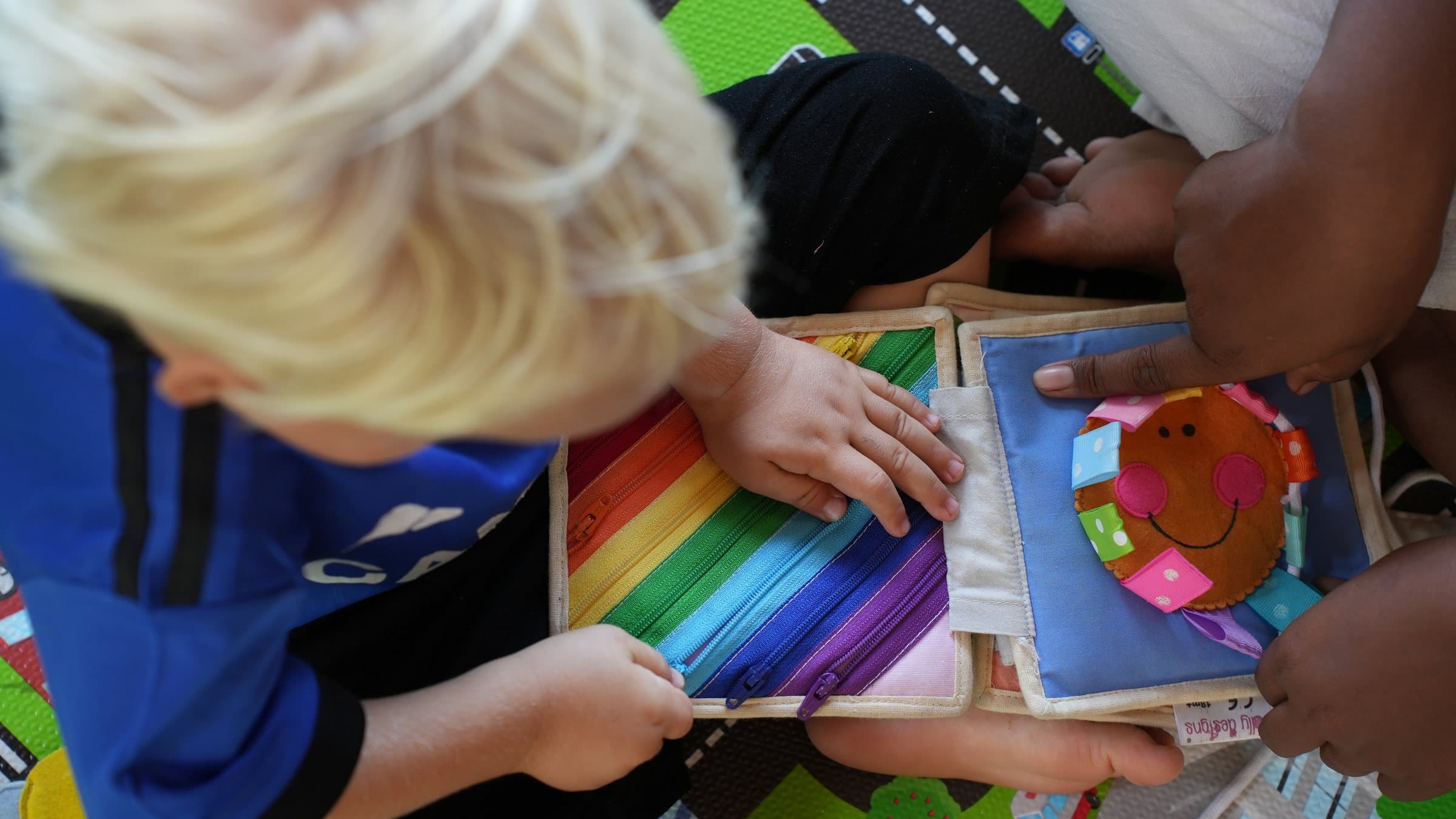 Toddlers exploring a sensory play book together at Selong Bay School