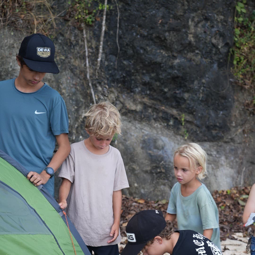 Children pitching a tent together on the beach during a camp out