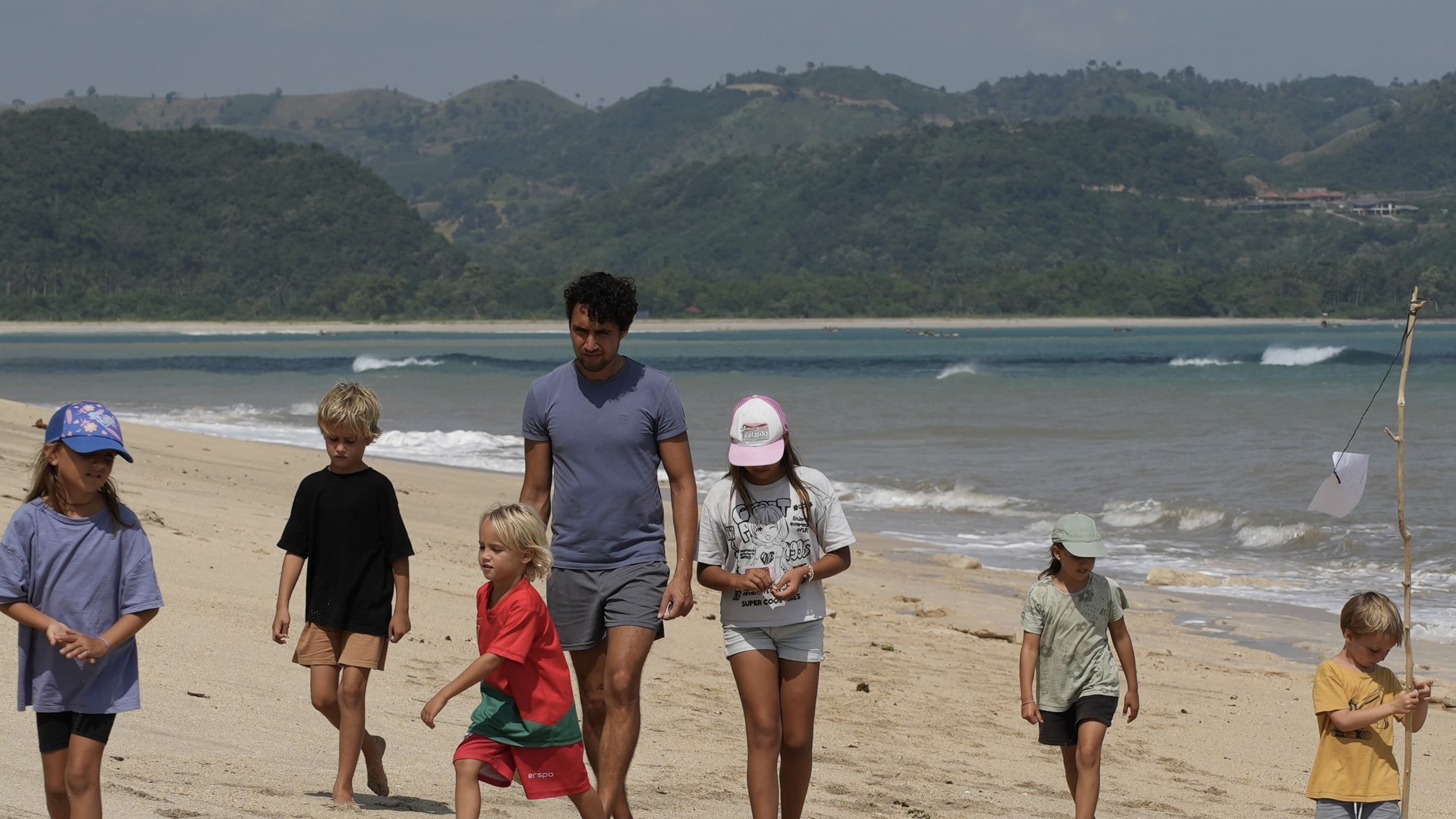 A father walking along the beach at Selong Belanak with a group of children