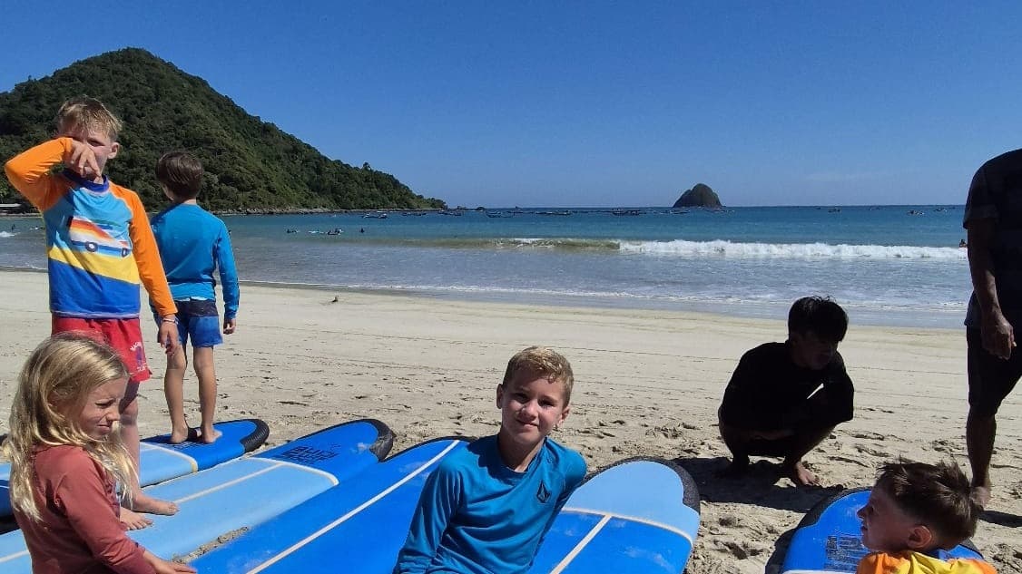 Children sitting on surfboards on the beach at Selong Belanak during a surf session