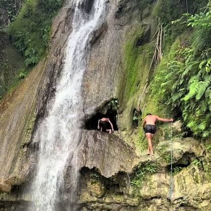 Visitors climbing near a waterfall on a Lombok waterfall trek
